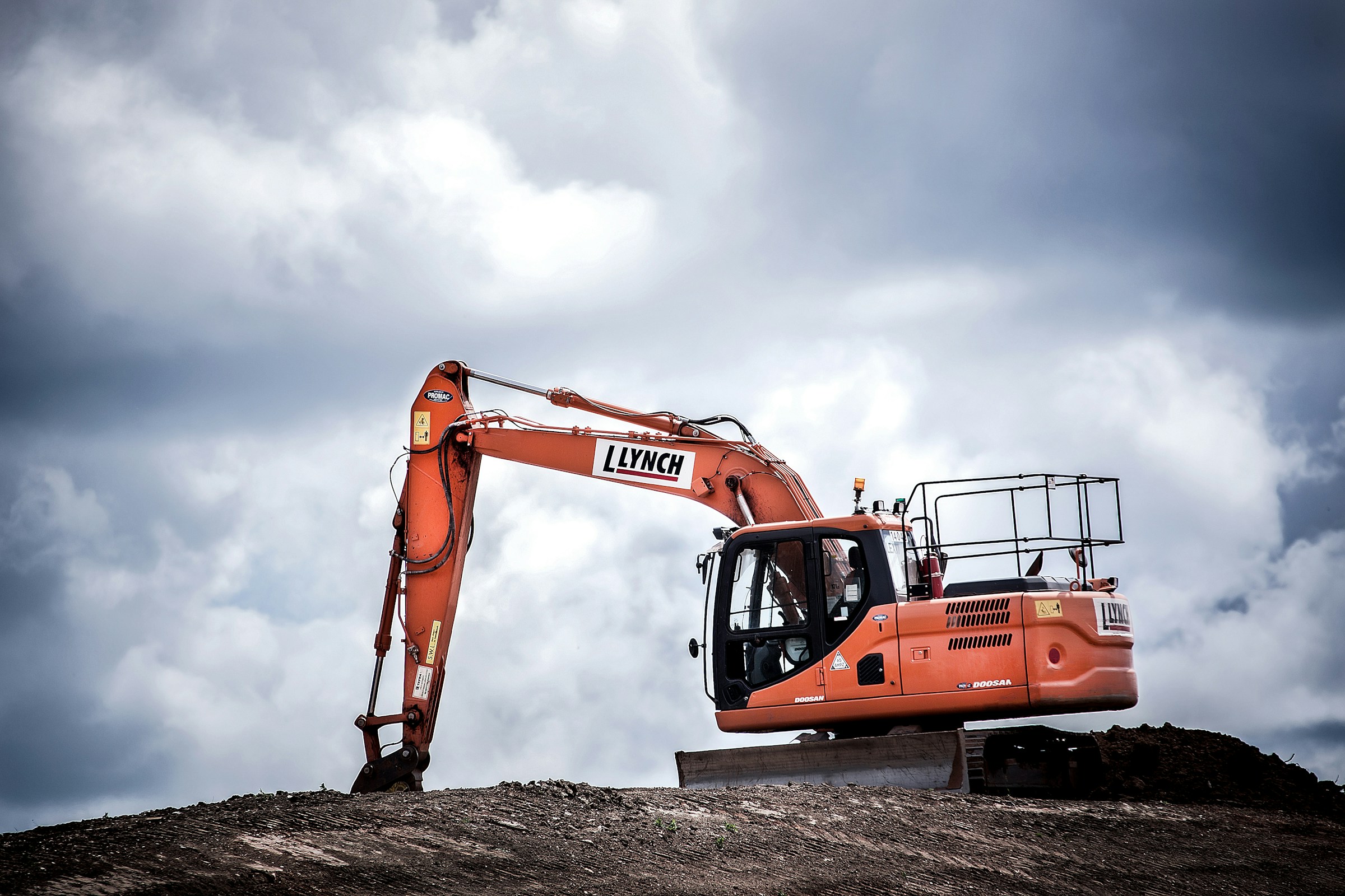 Orange excavator on an industrial worksite beneath a gray sky